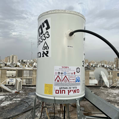 דוד שמש על גג עם מדבקות אזהרה וחיבורים