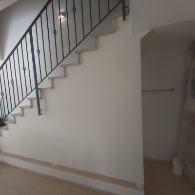 קיר גבס מתחת למדרגות עם מעקה מתכת שחור