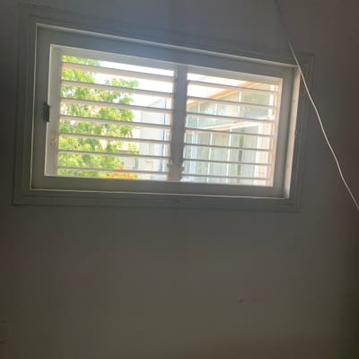 חלון זכוכית עם תריסים פתוחים ואור שמש נכנס