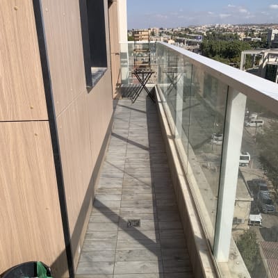 מרפסת פתוחה עם מעקה זכוכית וציוד ניקוי חלונות בדלי