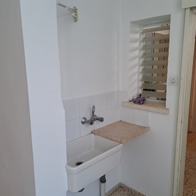 כיור לבן עם ברז מתכת על קיר לבן