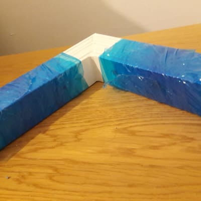 מסגרת לבנה עטופה בניילון כחול על שולחן עץ