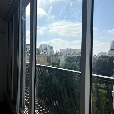 חלון אלומיניום עם נוף חיצוני של בניינים ועצים