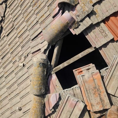 רעפים שבורים על גג עם חור גדול