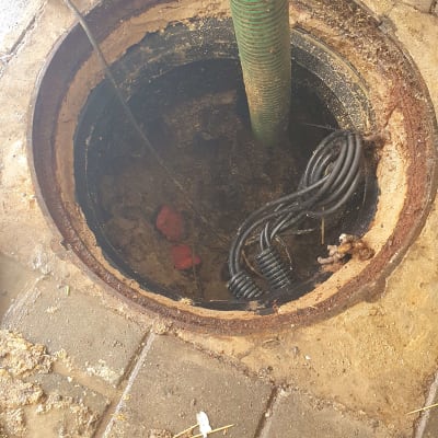 צינור ירוק נכנס לפתח ביוב עם כבלים