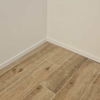 רצפת פרקט עץ בפינת חדר עם קיר לבן