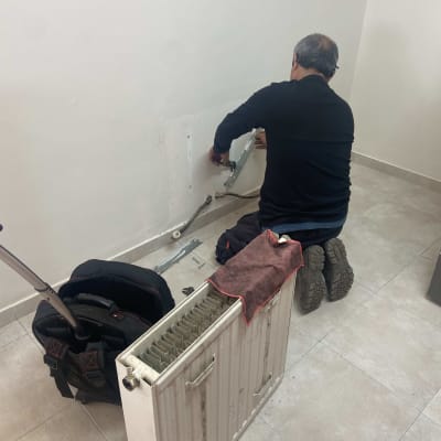 אדם מתקין רדיאטור על קיר בחדר.