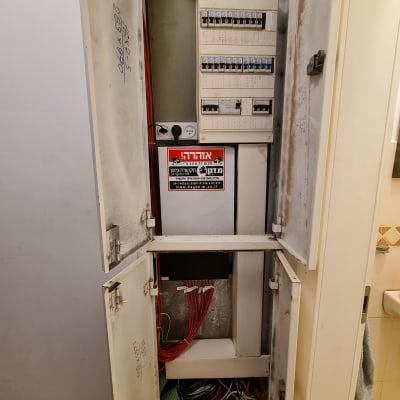 ארון חשמל פתוח עם כבלים אדומים ולוח מפסקים