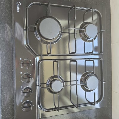 כיריים גז שחורות עם ארבעה מבערים וכפתורי שליטה