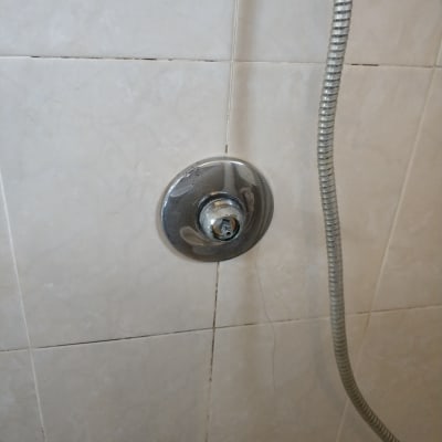 ברז מקלחת עם צינור מתכת על קיר אריחים