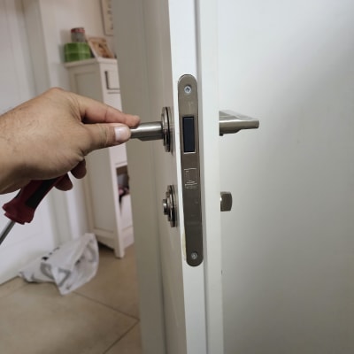 יד מחזיקה מברג ליד מנעול דלת