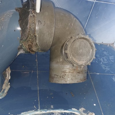 צינור ביוב עם חיבור חלוד ורצפה כחולה