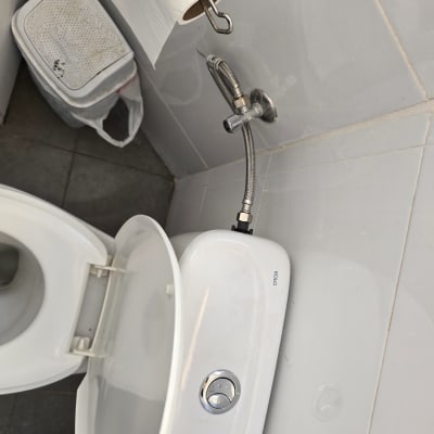 אסלה עם ניאגרה וצינור מים בחדר שירותים