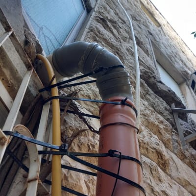 צינור פלסטיק מחובר לקיר אבן עם אזיקונים