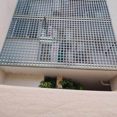 רשת מתכת על קיר עם צינור ומיכלים מאחוריה