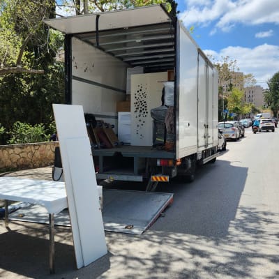 משאית פתוחה עם רהיטים ברחוב ביום שמש
