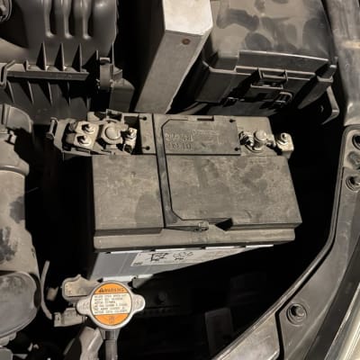 מצבר רכב עם חיבורים וכבלים במכסה מנוע