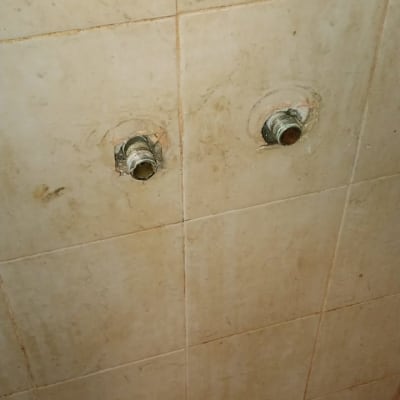 צינורות מים חשופים בקיר אמבטיה עם ברז ישן