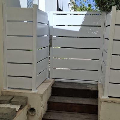 שער לבן עם מדרגות ועצים ברקע