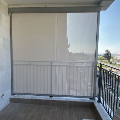 מרפסת עם סוכך גלילה חצי שקוף על מעקה ברזל