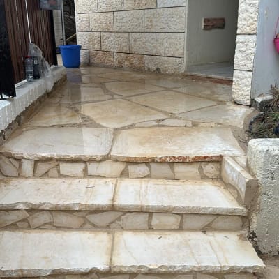 מדרגות אבן רטובות עם דלי כחול בצד