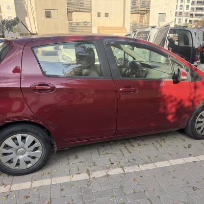 רכב אדום חונה בחניון עם כלי ניקוי ברקע
