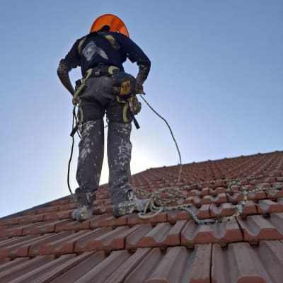 עובד על גג רעפים עם ציוד בטיחות