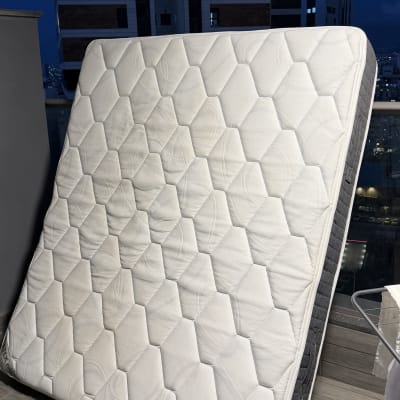 מזרן עומד על מרפסת עם רקע של בניינים בלילה