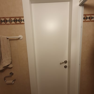 דלת לבנה עם ידית מתכת בחדר אמבטיה
