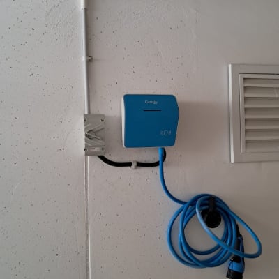 מטען חשמלי כחול עם כבל תלוי על קיר