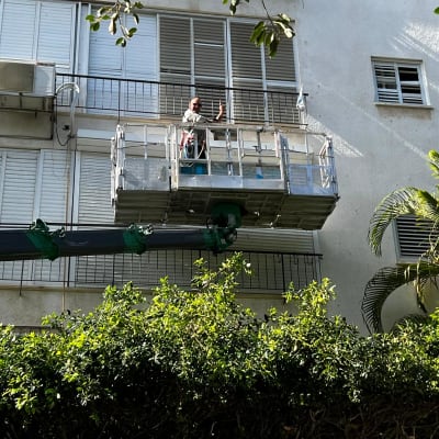 אדם על פיגום מול תריסים בבניין