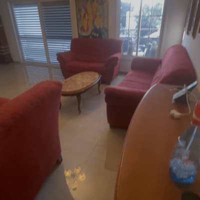 בקבוק חומר ניקוי על שולחן בסלון עם ספות אדומות