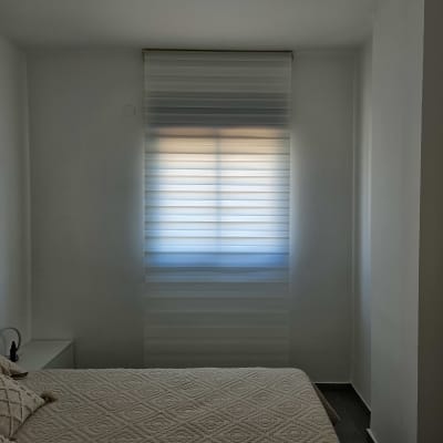 חדר עם מנורה תלויה ותריסים על החלון