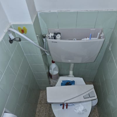 תמונה של שירותים עם מיכל הדחה פתוח וכלים