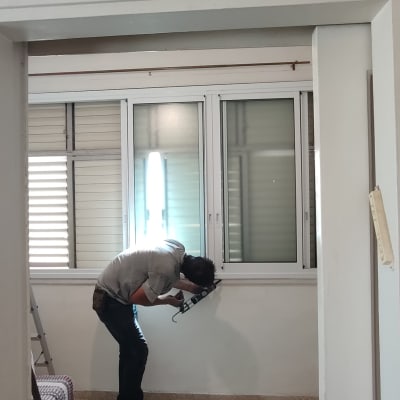 אדם עובד על חלון אלומיניום עם כלי עבודה