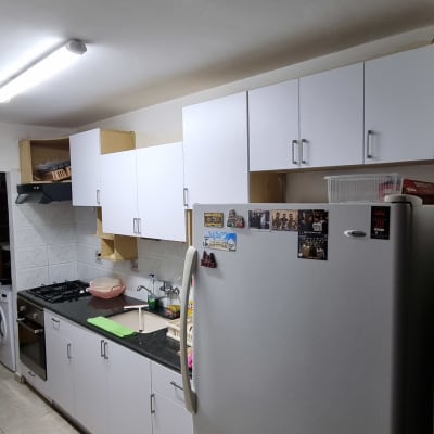 מטבח עם מקרר, ארונות לבנים וכיריים גז