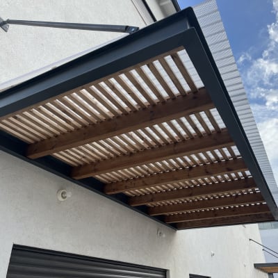 פרגולה מעץ ומתכת מחוברת לקיר חיצוני