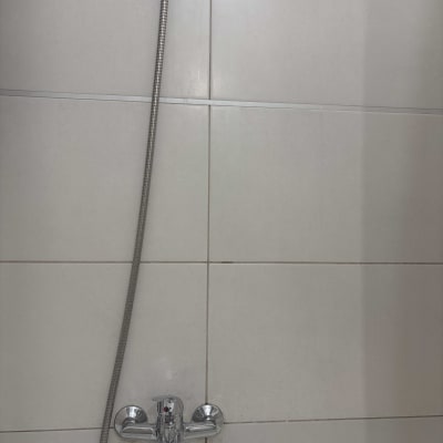 ברז מקלחת עם צינור מתכת על קיר אריחים