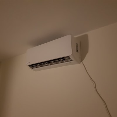 מזגן קיר לבן מותקן על קיר עם כבל חשמל