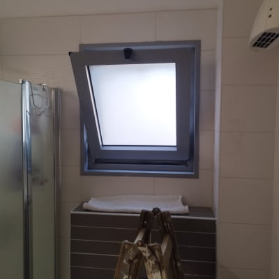 חלון עם תריס פתוח למחצה בחדר אמבטיה