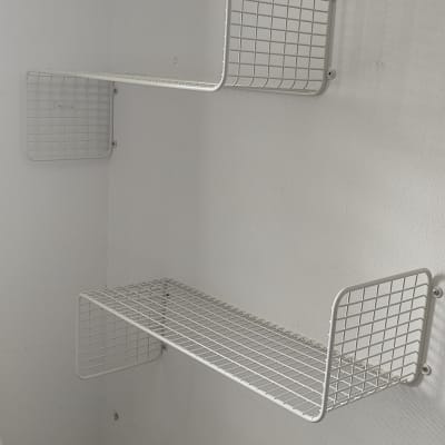 מדפי רשת מתכתיים מותקנים על קיר לבן