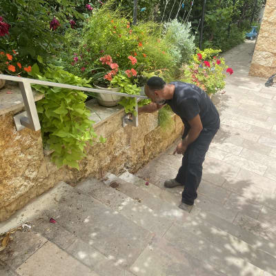 אדם מתקין מעקה מתכת על מדרגות אבן