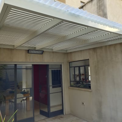 פרגולה מאלומיניום מחוברת לקיר חיצוני של בית