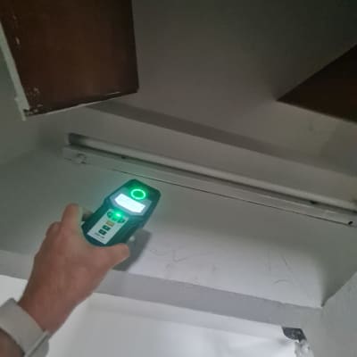 יד מחזיקה מכשיר מדידה מתחת למדף