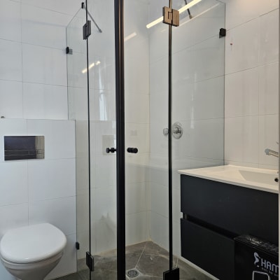 מקלחון זכוכית עם דלתות שחורות בחדר אמבטיה