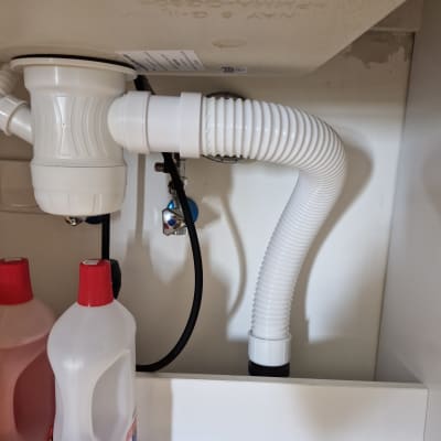 צינור ניקוז מתחת לכיור עם בקבוקי חומרי ניקוי