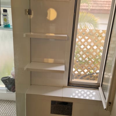 מדף עץ לבן מותקן על קיר ליד חלון