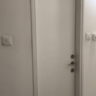 דלת לבנה עם ידית מתכת ומתגים על הקיר