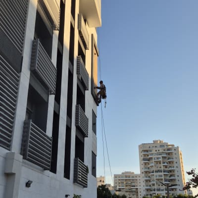 אדם תלוי על חבל מתקין רשתות על בניין