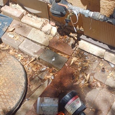 כלים וחלקים של אינסטלציה על רצפה ליד צינורות מים